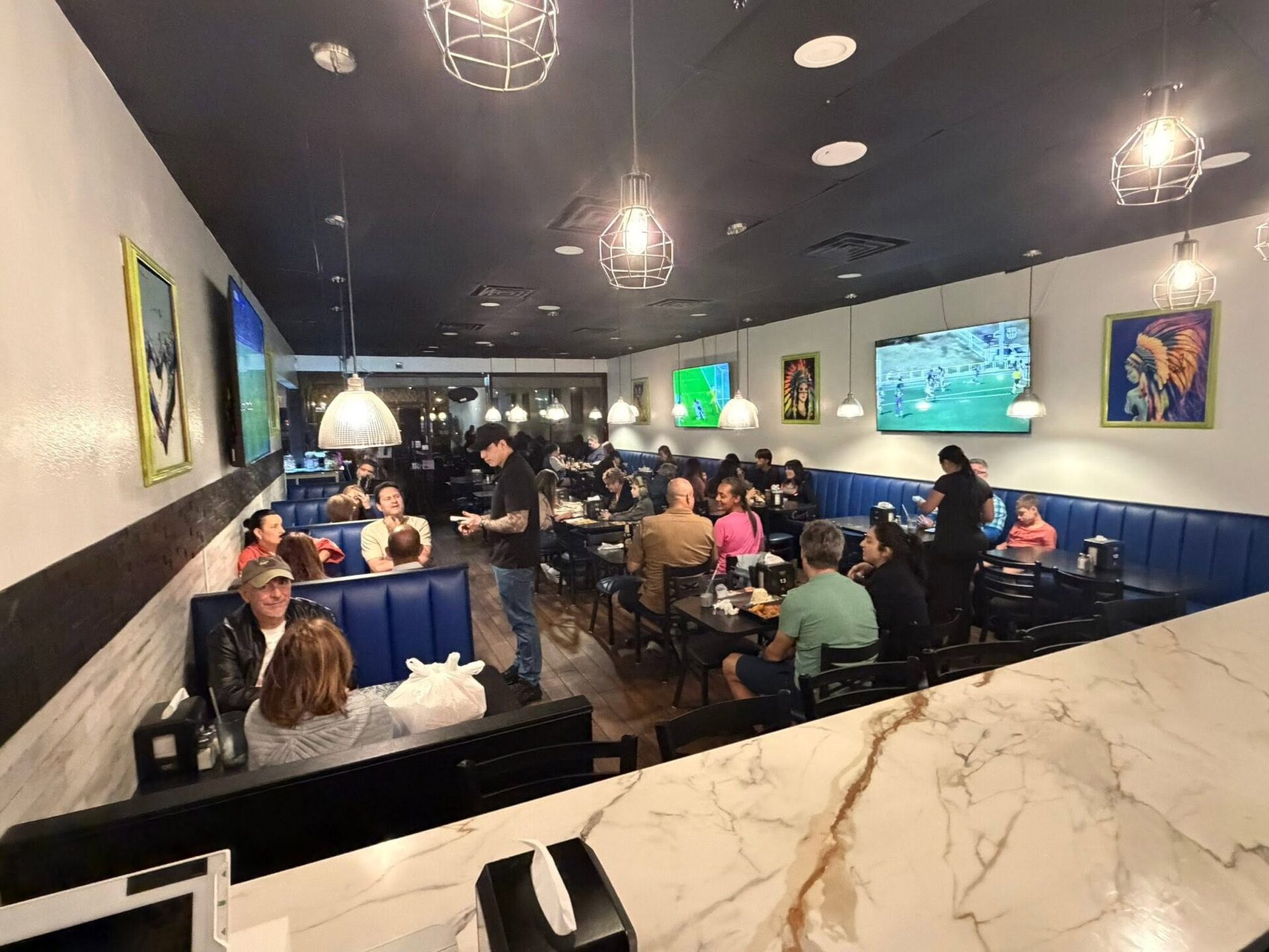 Inside Mi Carreta: a full dining room of families and blue booths under pendant lights
