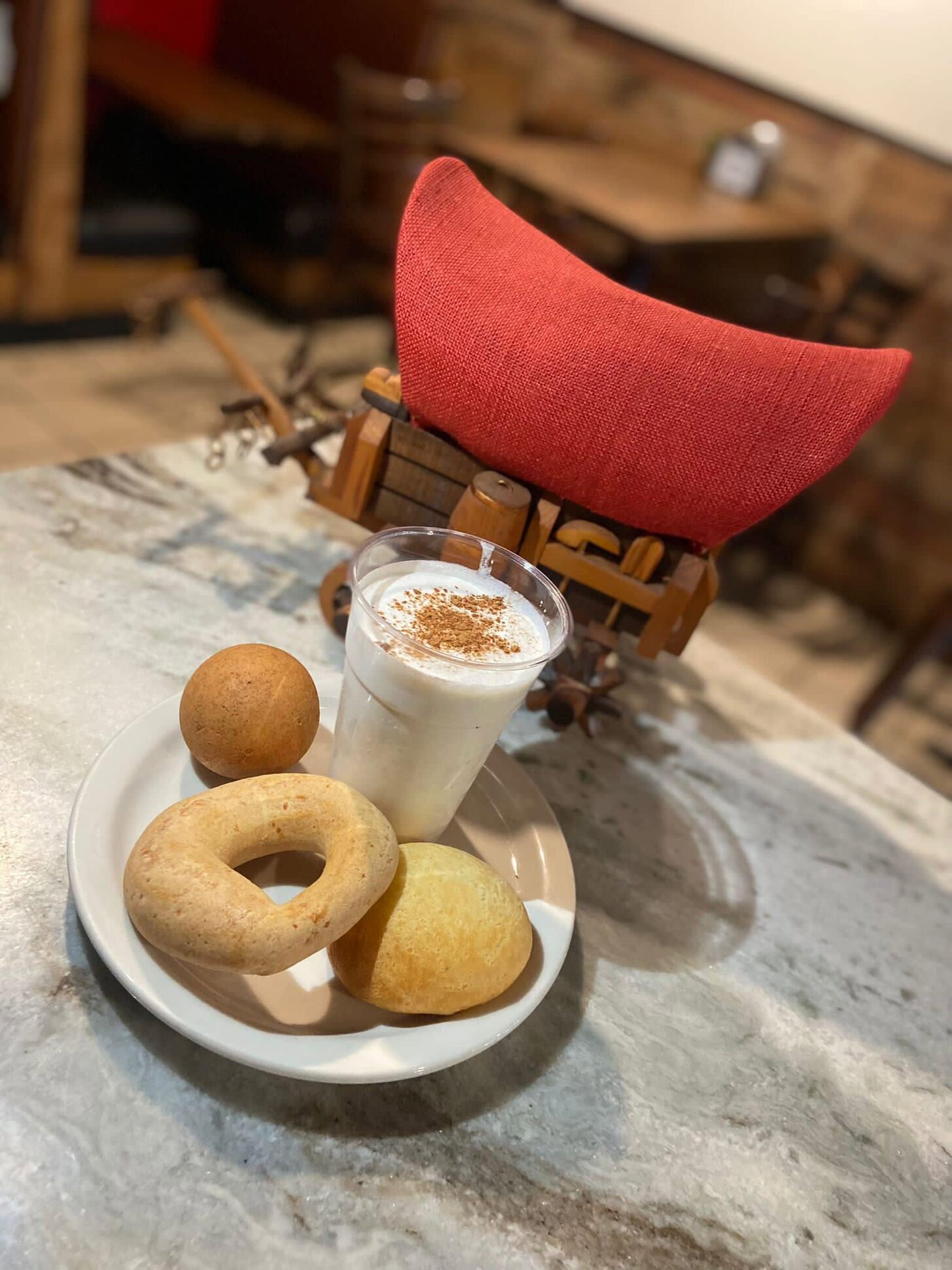 Café con leche with a pandebono and buñuelo beside a little wagon
