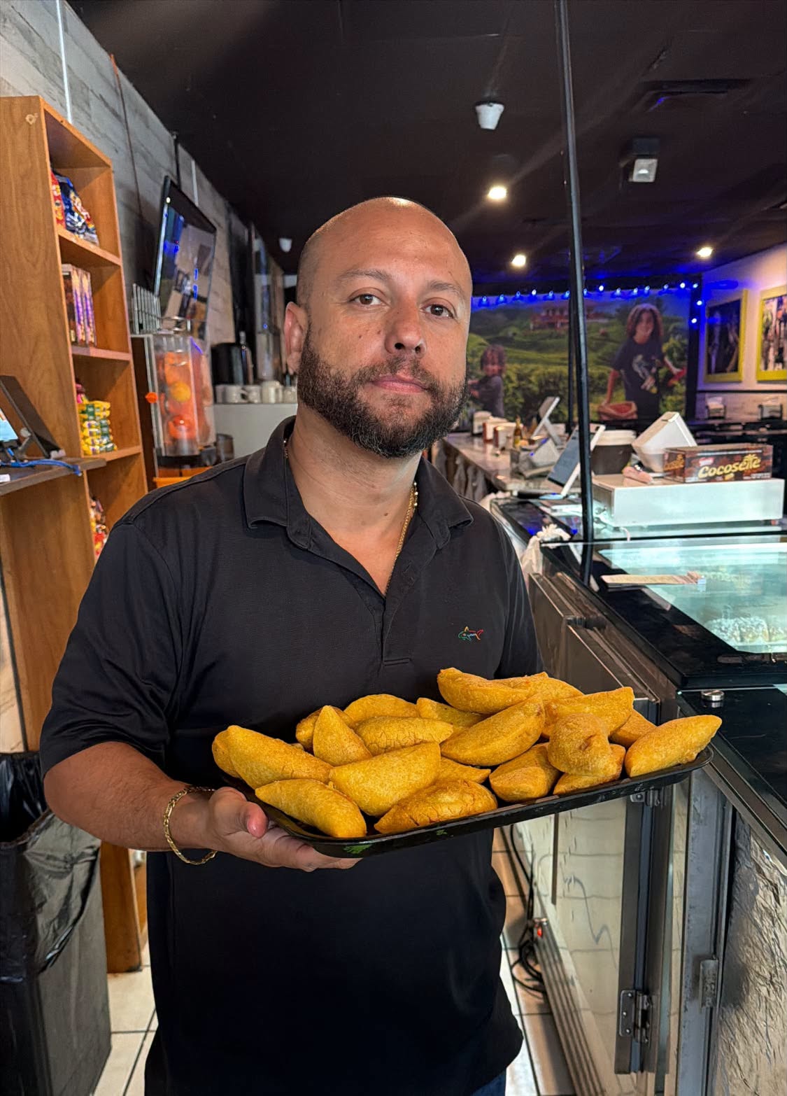 A Mi Carreta team member holding out a tray of fresh empanadas