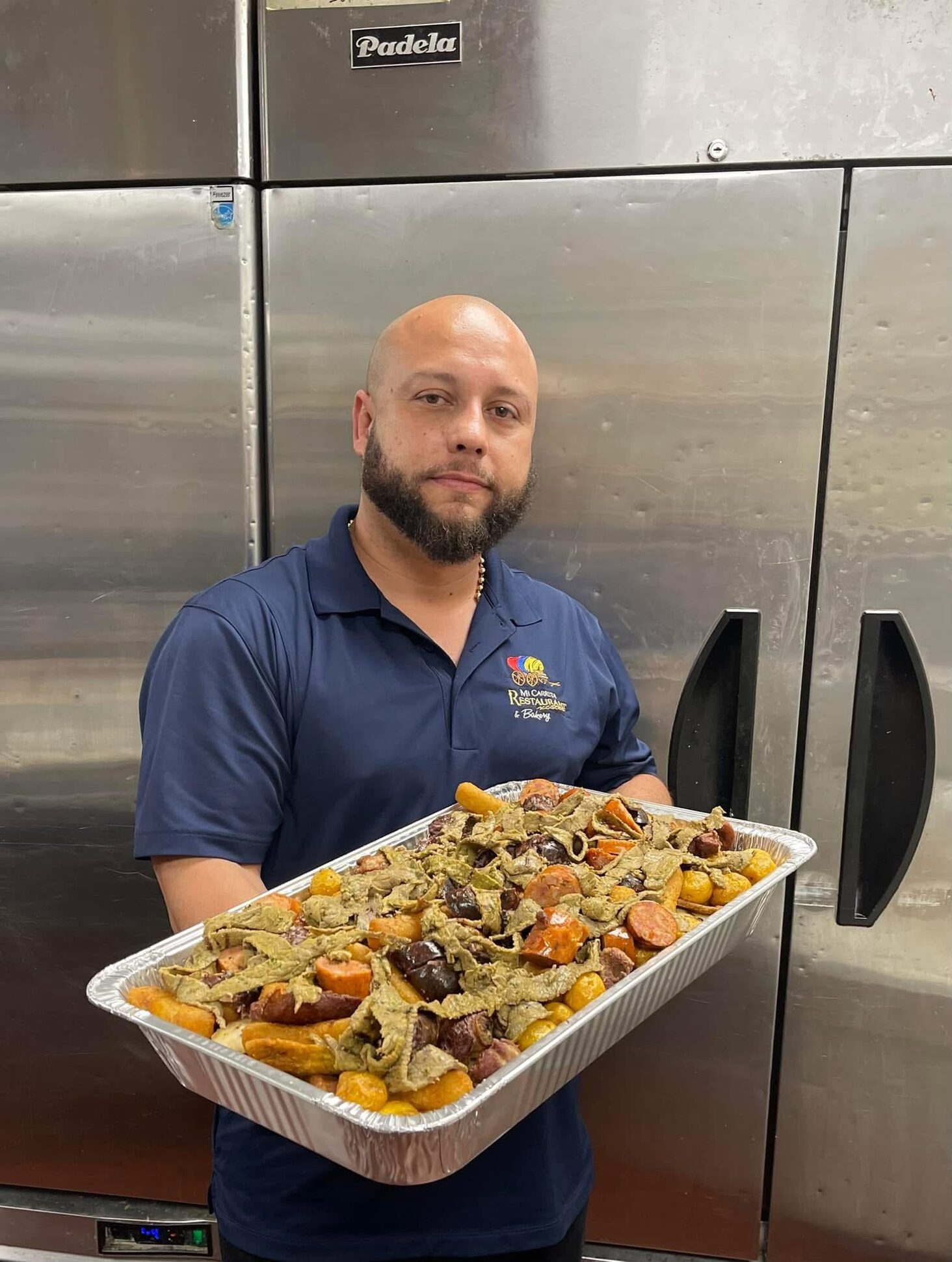 A Mi Carreta team member holding a full party tray in the kitchen