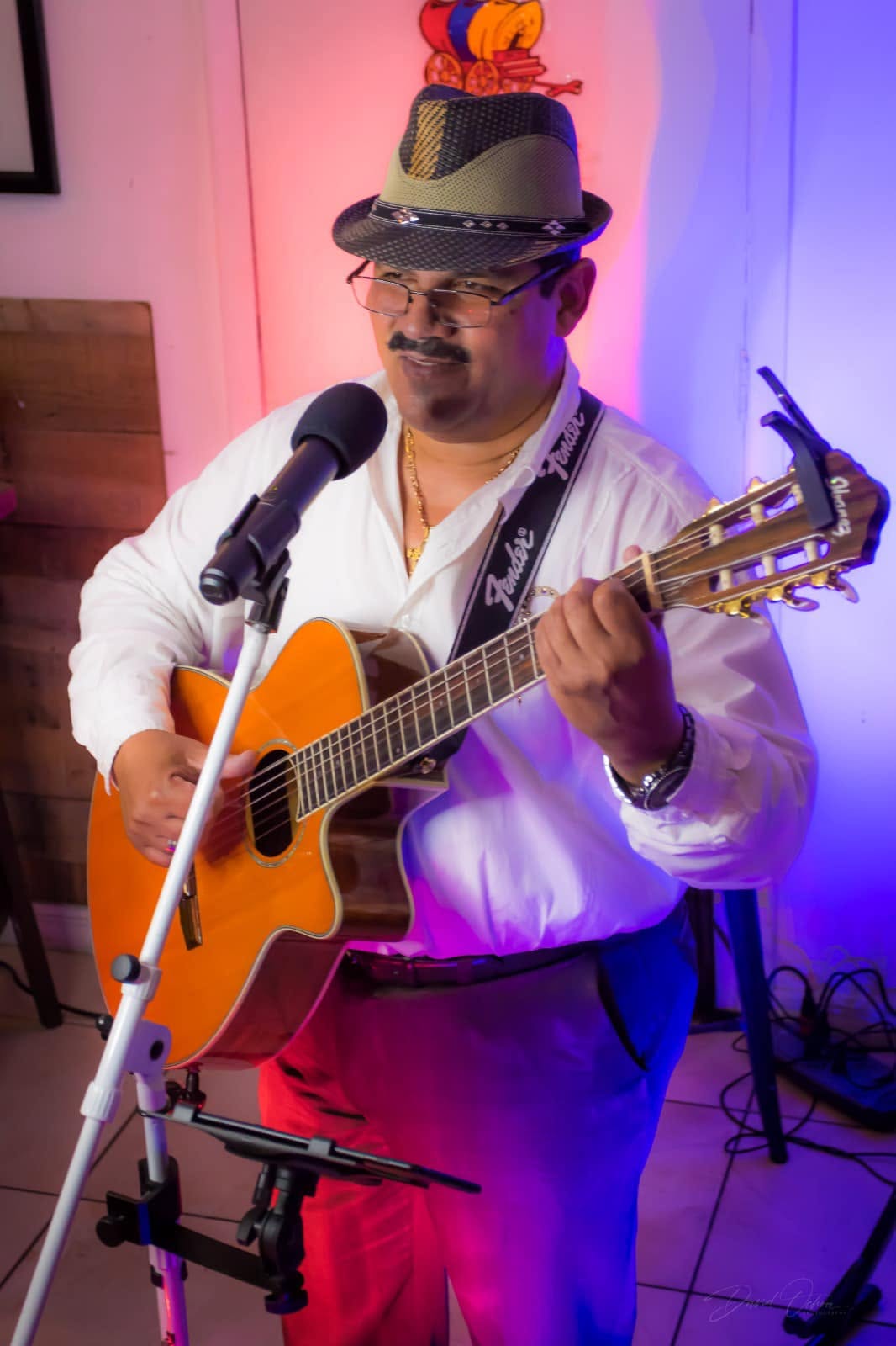 A singer with an acoustic guitar under red and blue light