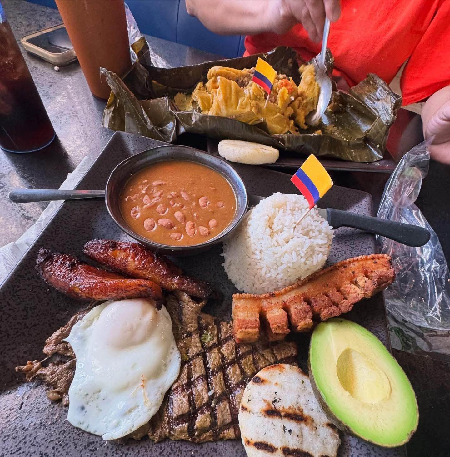 A table spread with tamal, bandeja, beans, avocado and fried egg