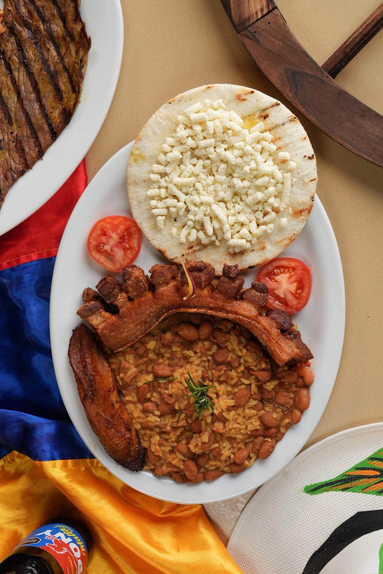 Calentado with crisp pork belly and a white arepa on a plate set over the Colombian flag