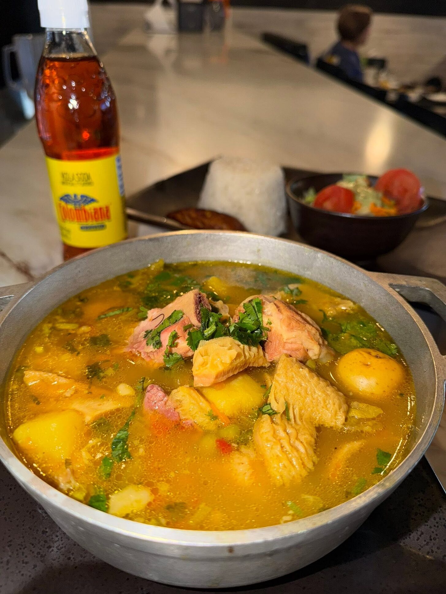 A pot of chicken soup with potato and cilantro