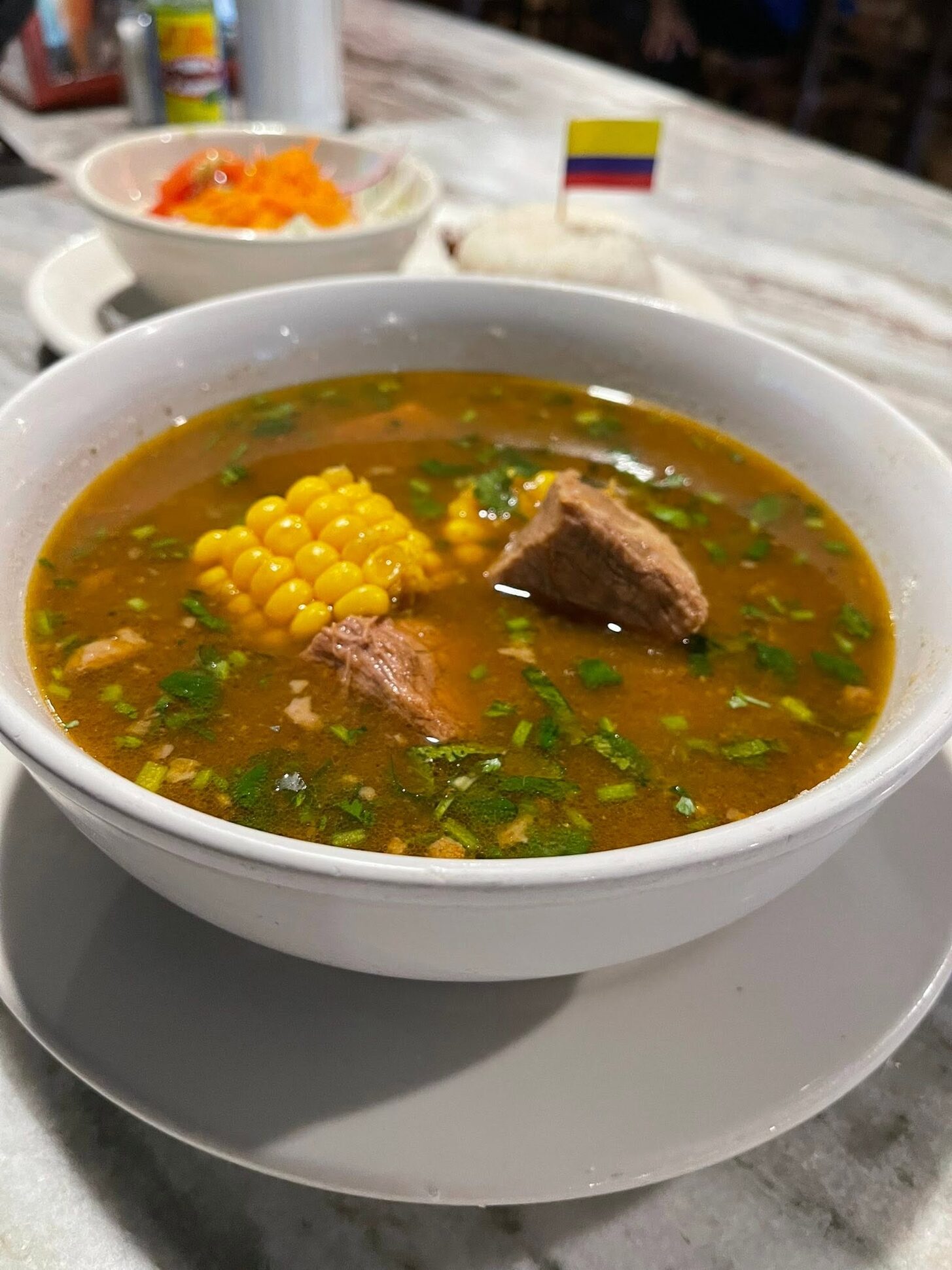 A deep bowl of sancocho with beef and corn on the cob