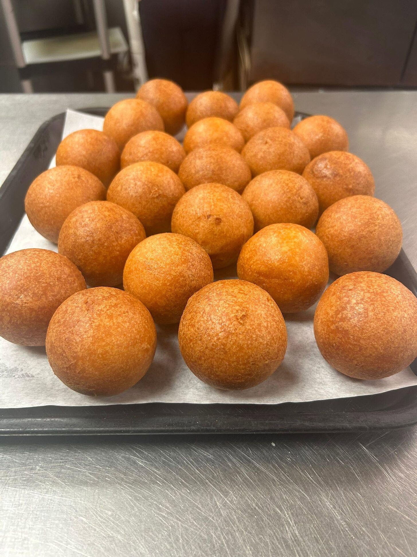Rows of buñuelos on a sheet pan