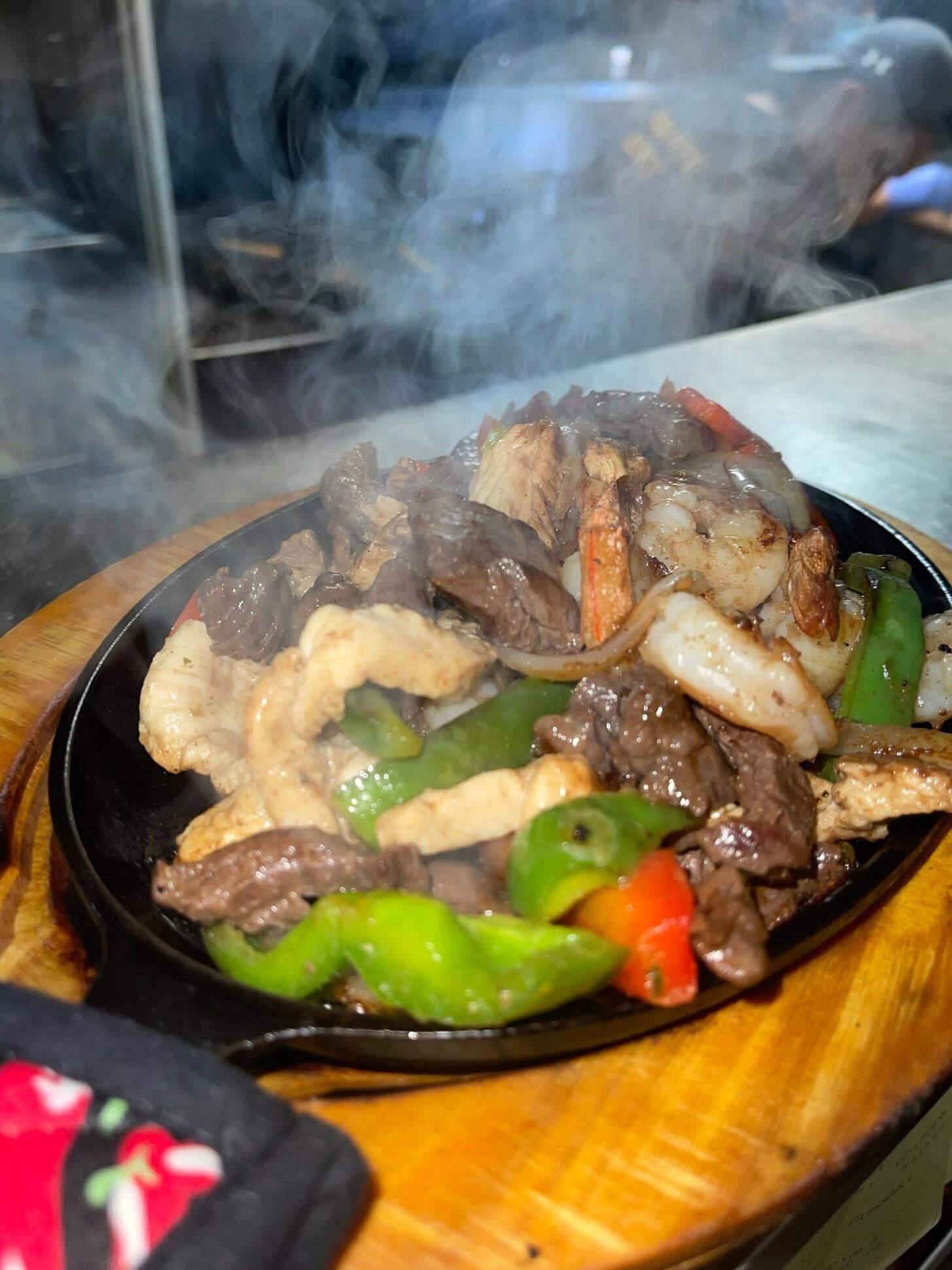 Steak and shrimp fajitas smoking on a cast-iron skillet