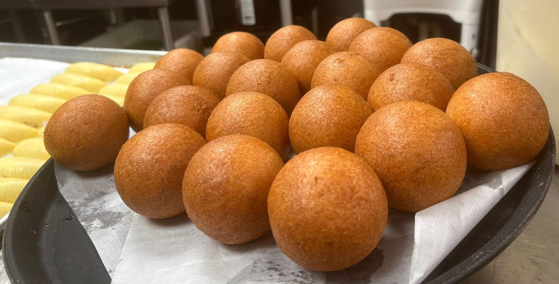 Golden buñuelos lined up on a tray