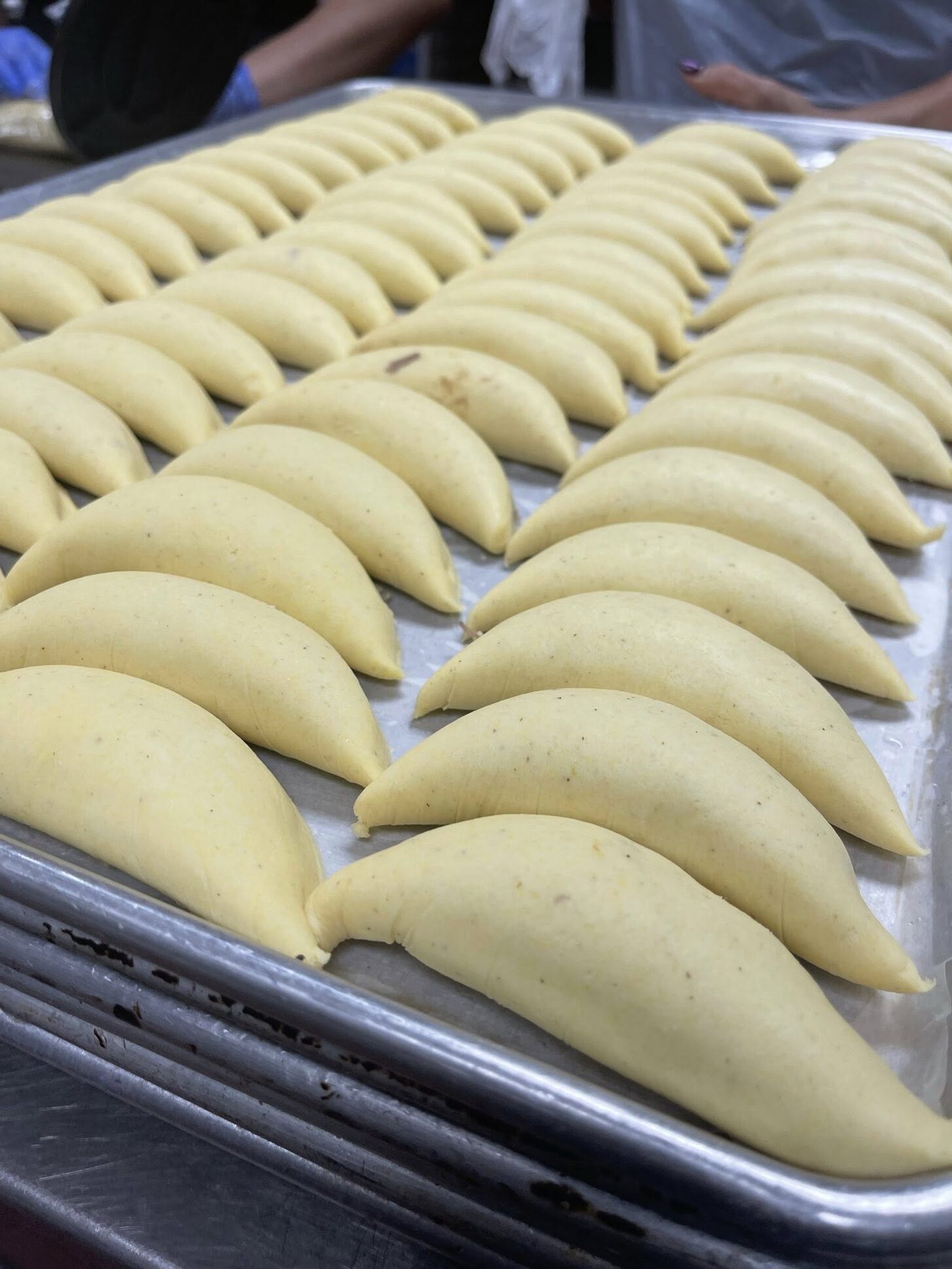 Rows of shaped, unbaked empanadas on a sheet pan