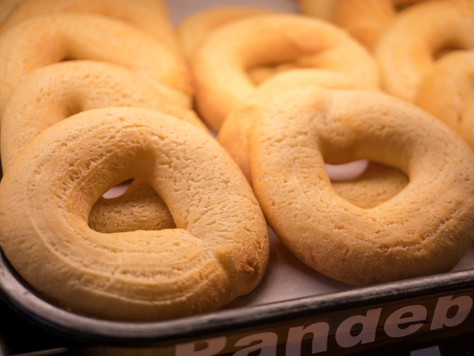 Rings of fresh pandebono on a bakery tray