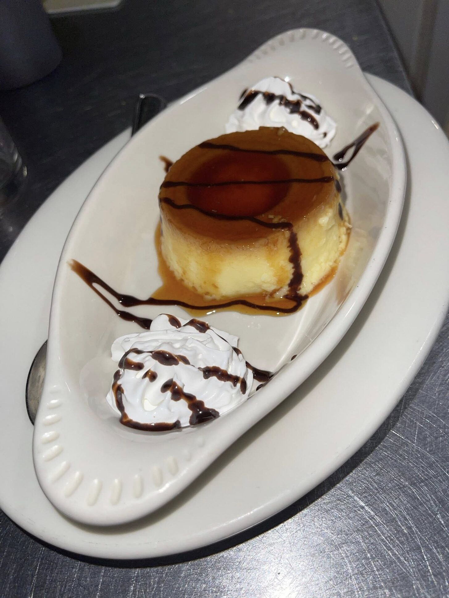 A slice of flan with whipped cream and chocolate